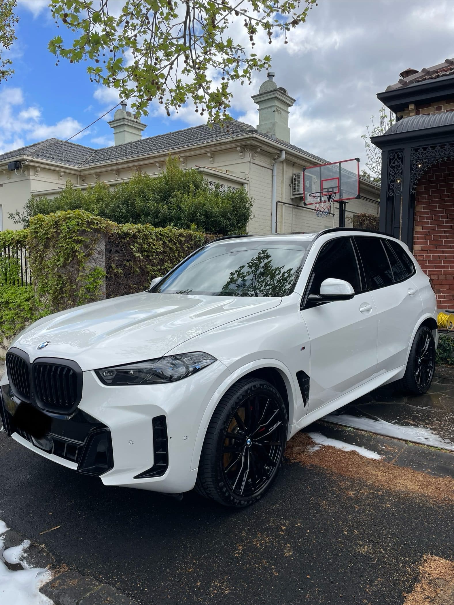 Front three-quarter view of a white BMW X5 parked in a driveway
