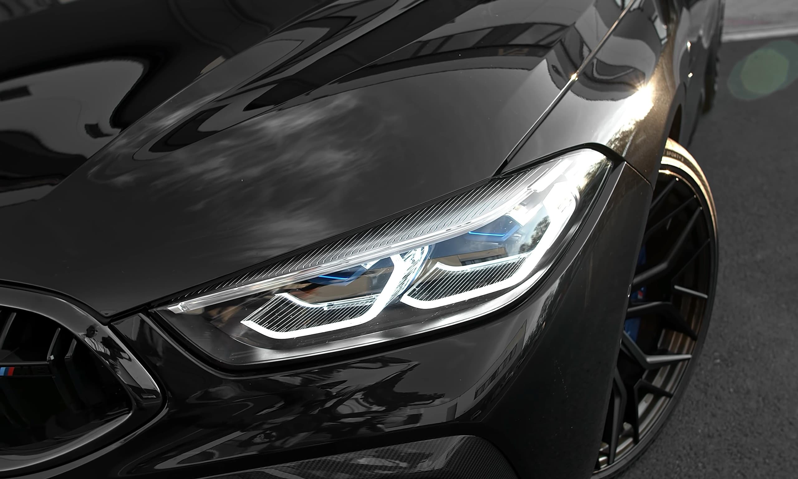 Close-up of a dark BMW headlight and glossy bonnet