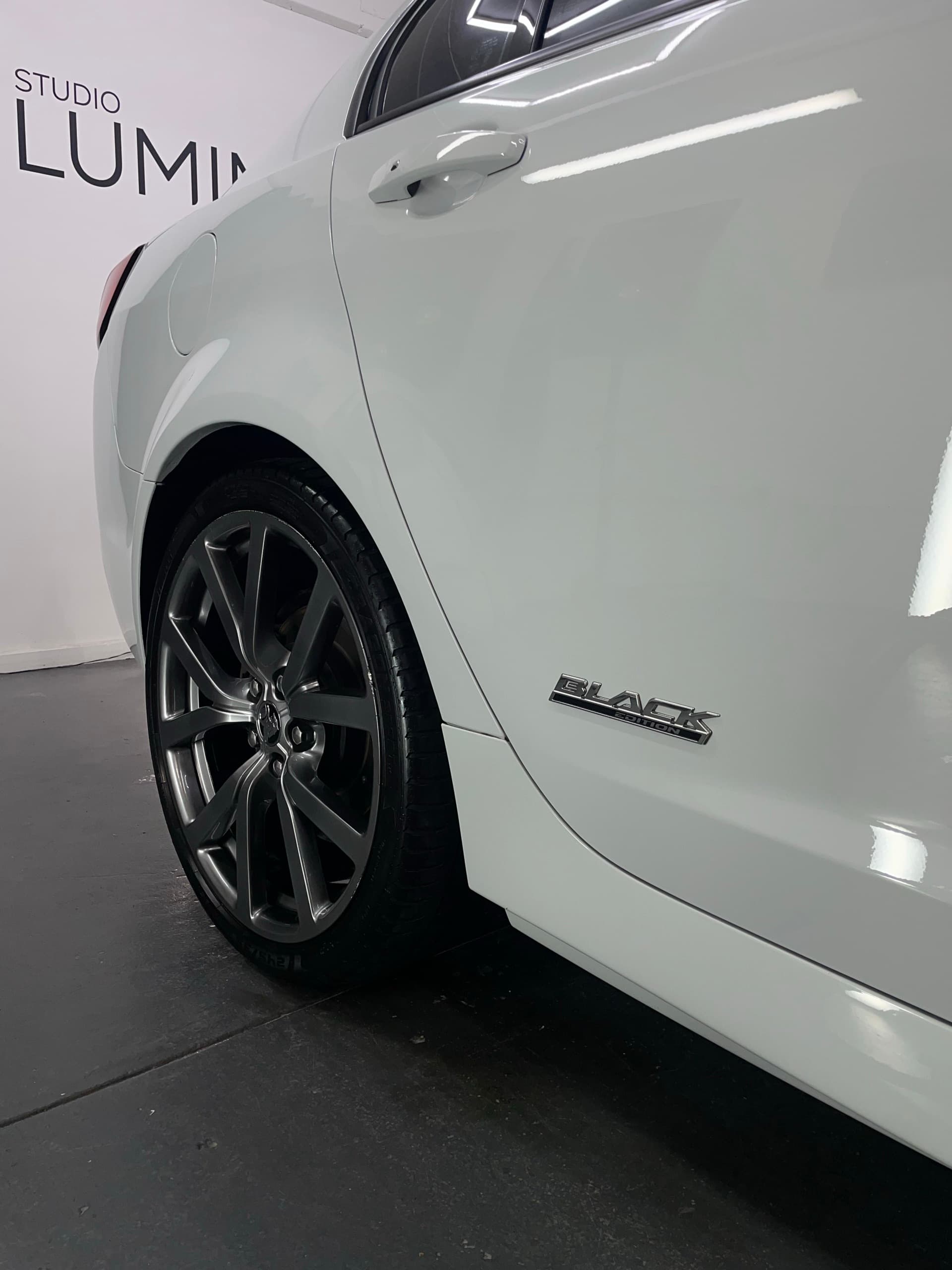 Rear quarter of a white Holden SV6 Black Edition with a dark alloy wheel and Black badge on the glossy paint