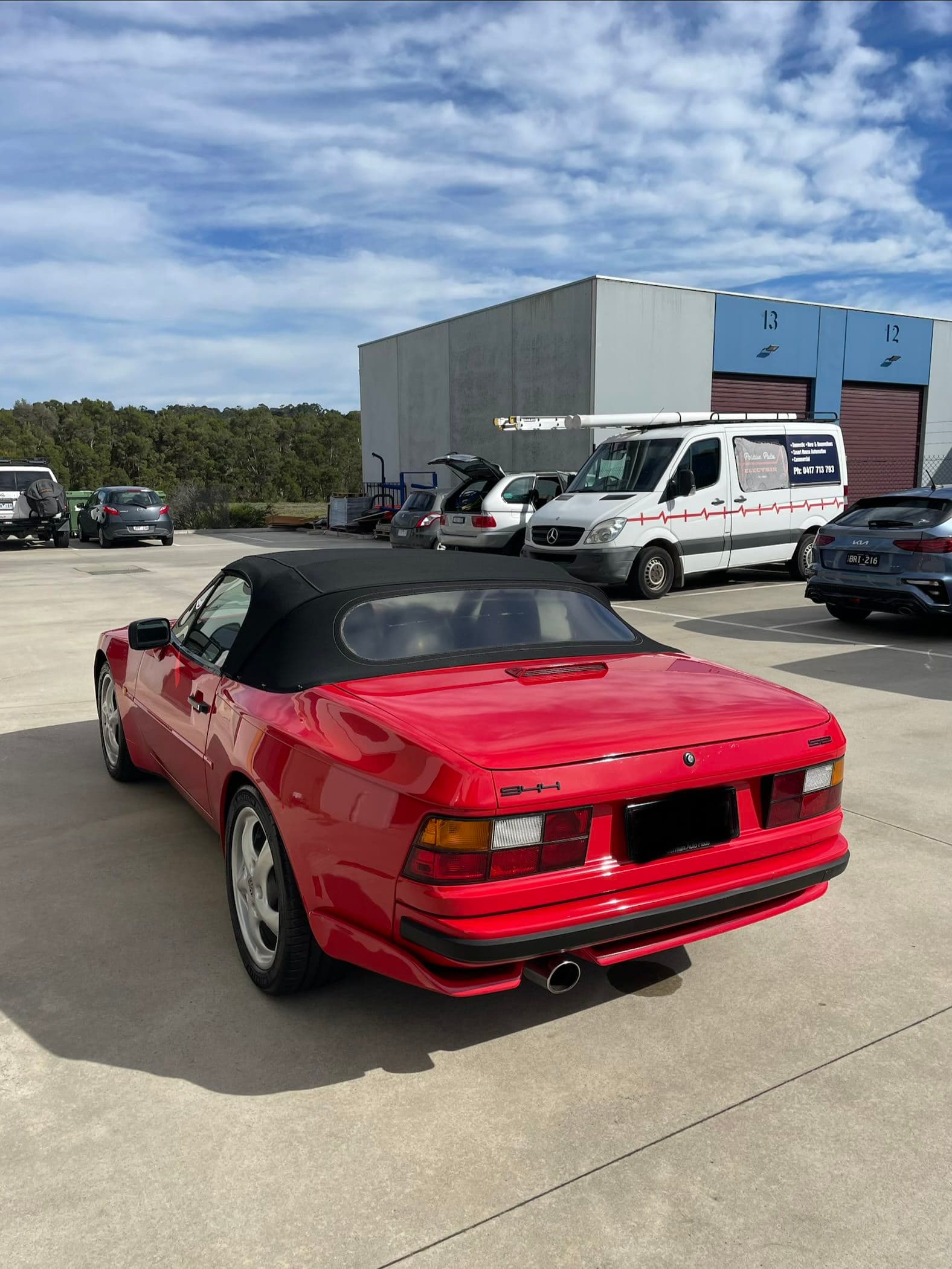 Rear three-quarter view of a red Porsche 944 S2 cabriolet in an industrial car park
