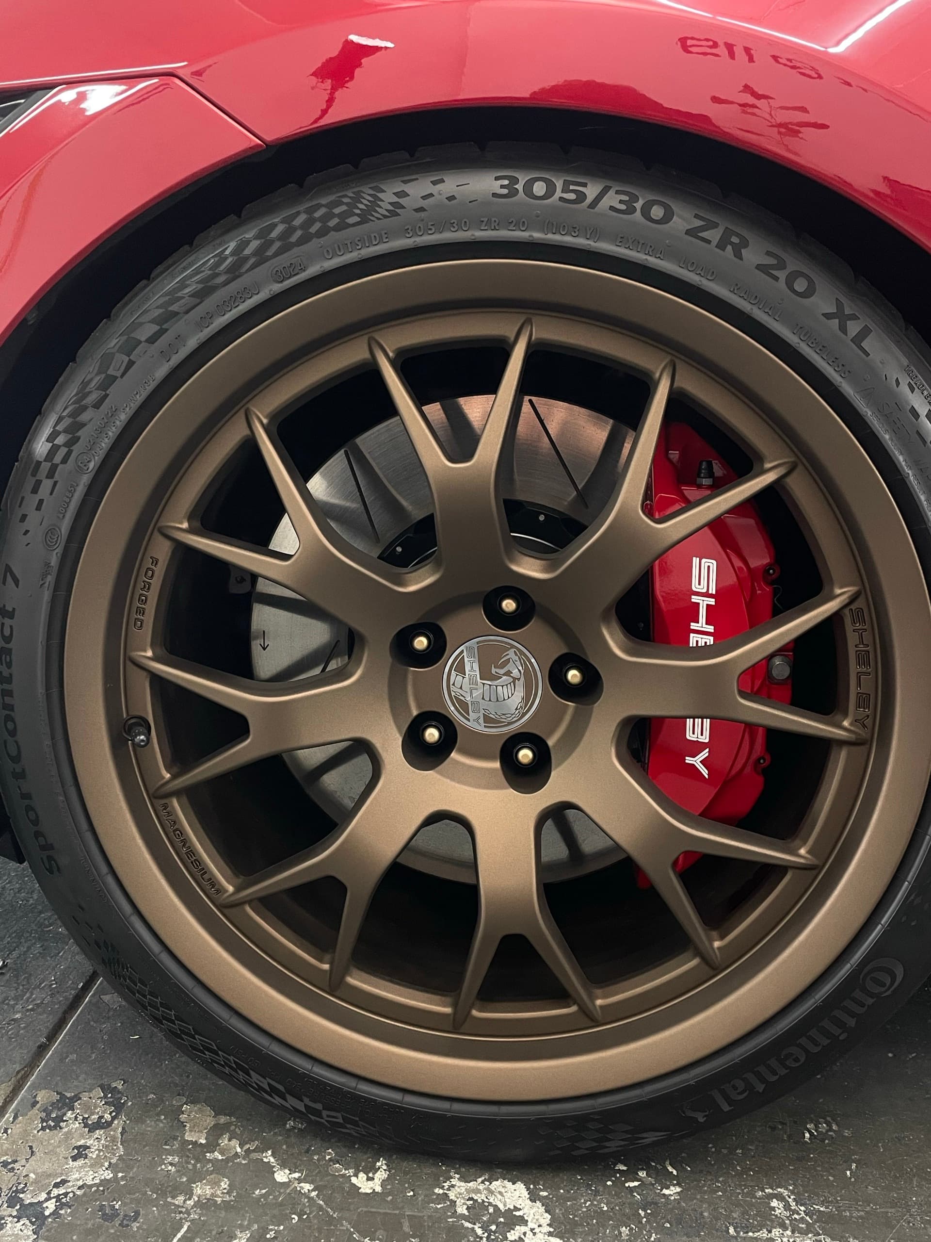 Bronze alloy wheel and red Shelby brake caliper on a red Ford Mustang